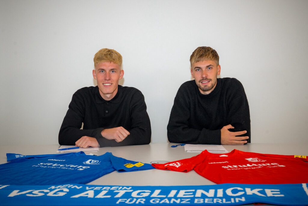 Paul Manske und Johannes Manske sitzen an einem Tisch, vor ihnen jeweils ein Trikot der VSG Altglienicke
